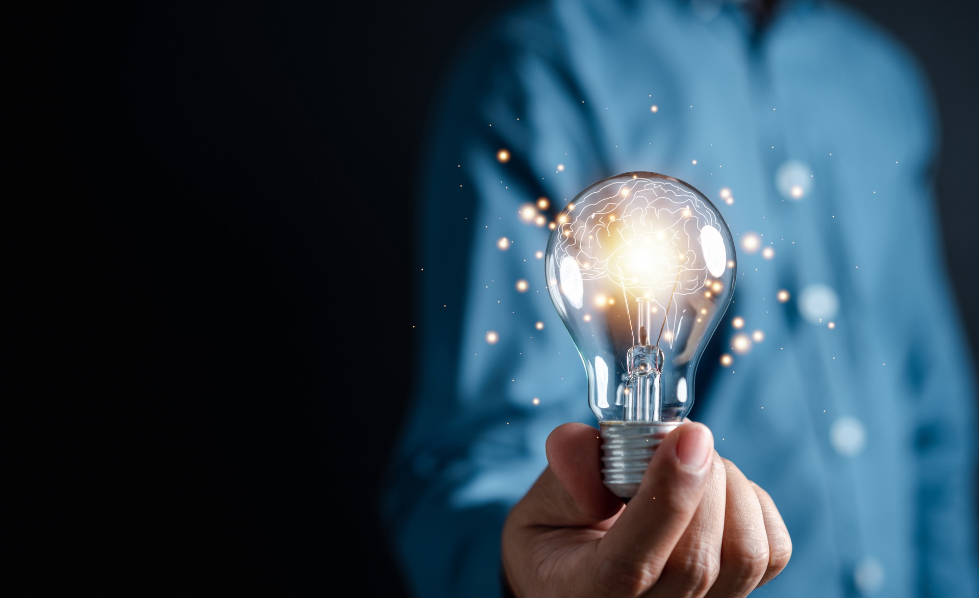 Innovation through ideas and inspiration ideas. Human hand holding light bulb to illuminate, idea of creativity and inspiration concept of sustainable business development.